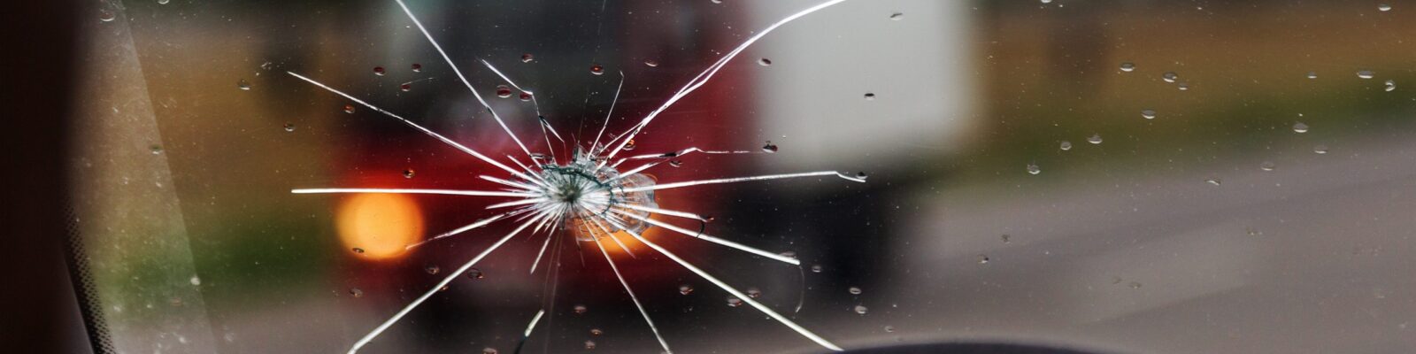 Parebrise éclat Broken windshield of a car. A web of radial splits, cracks on the triplex windshield. Broken car windshield, damaged glass with traces of oncoming stone on road or from bullet trace in car glass